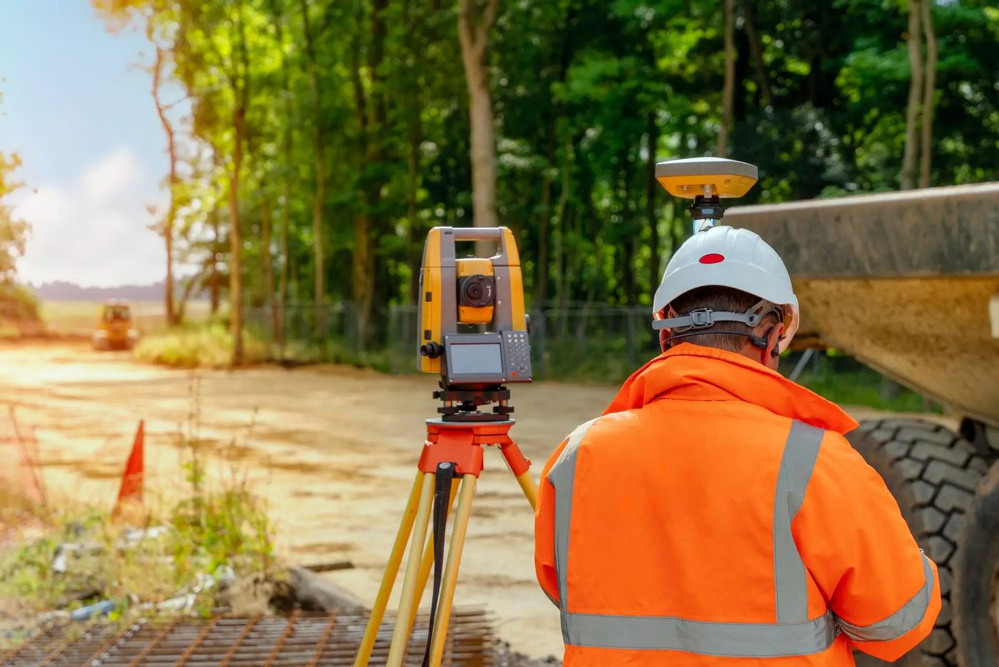 Surveyor in hi-vis setting out a site with a total station
